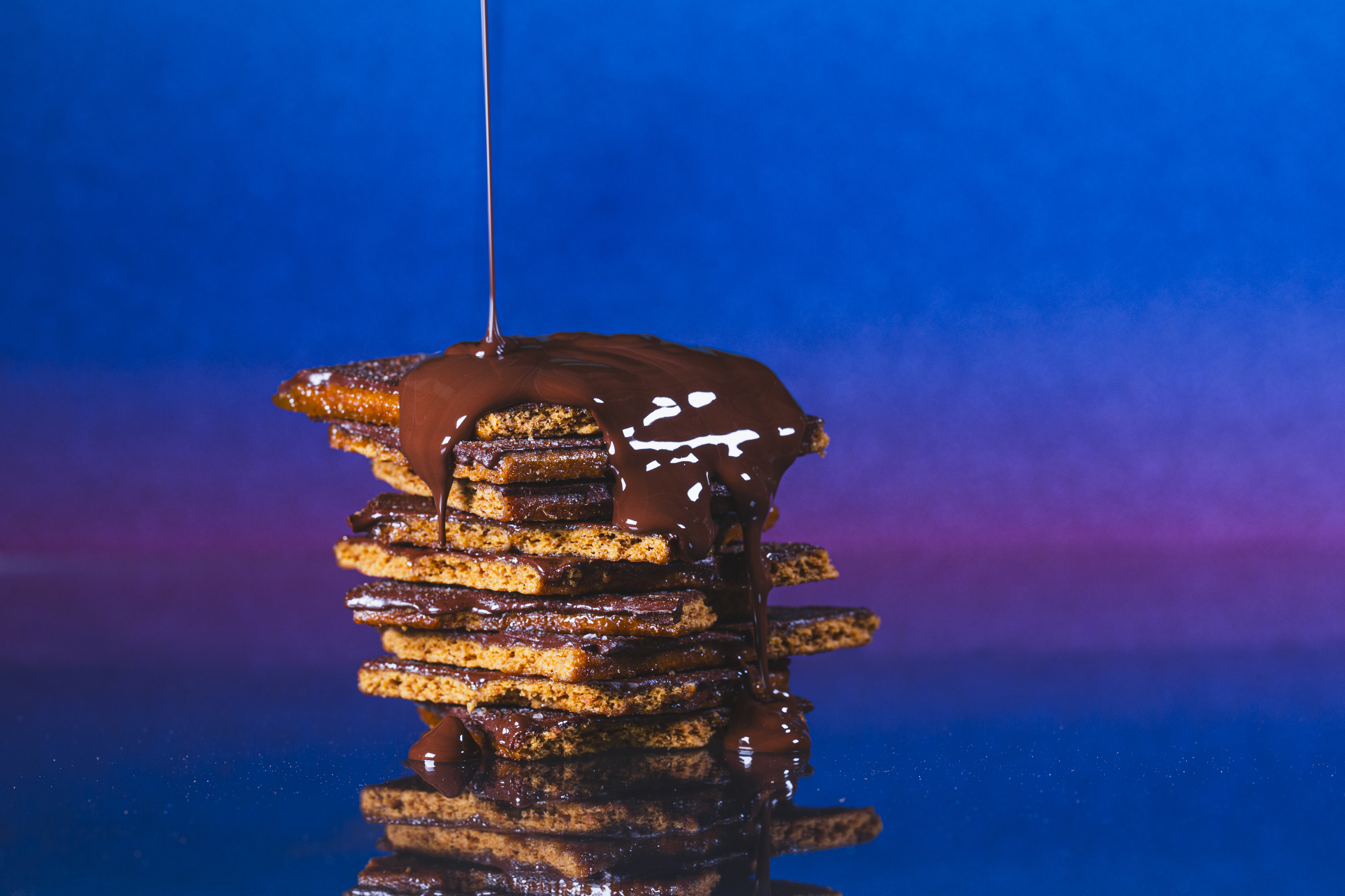 Melted chocolate pouring over a stack of Legally Addictive cookies